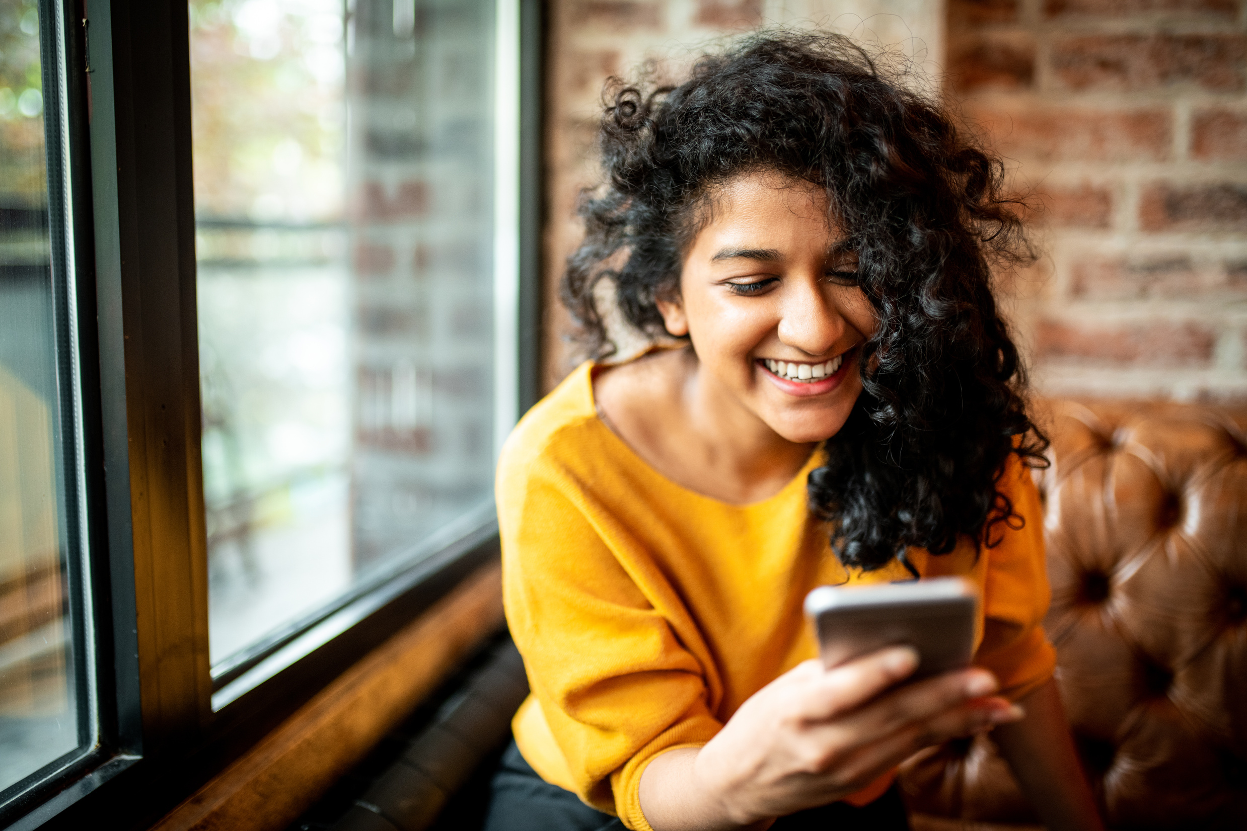 Smiling Indian woman using mobile phone.