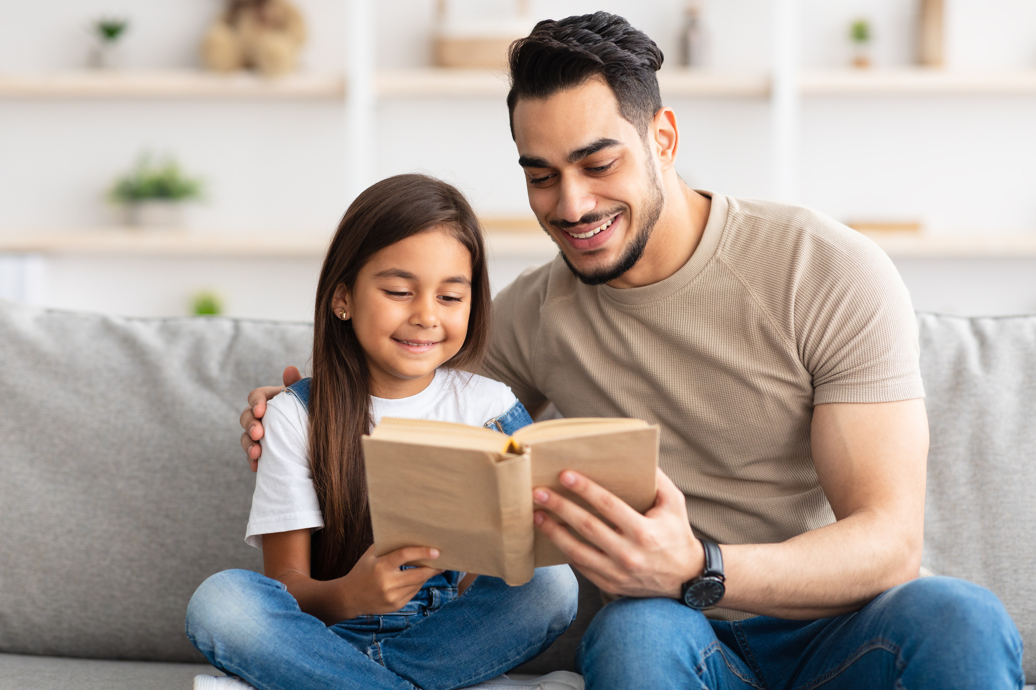 Dad and daughter reading book spending time together at home